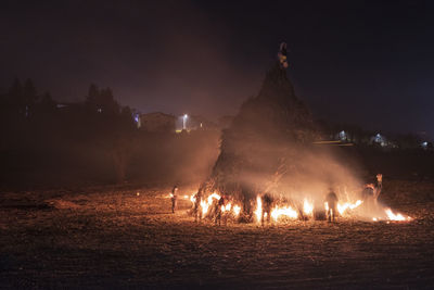 People standing by bonfire at night