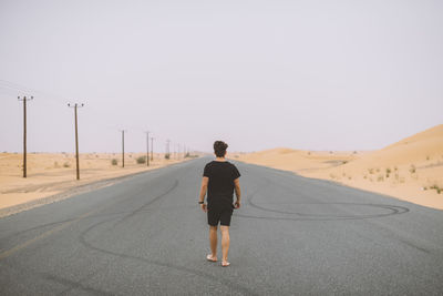 Rear view of man on road against clear sky