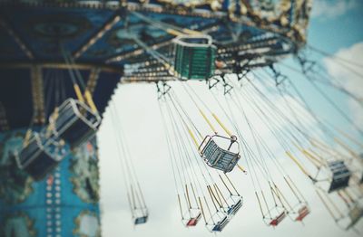Low angle view of chain swing ride against sky