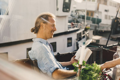 Smiling man with book looking away in houseboat