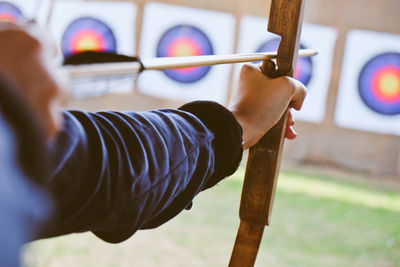 Cropped hands of woman with bow and arrow aiming at target