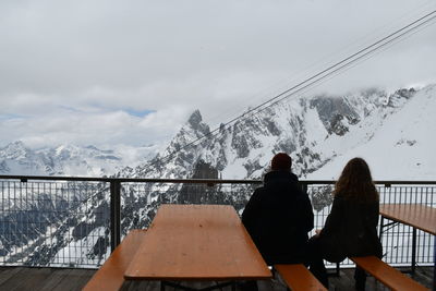 Rear view of women on snowcapped mountain against sky