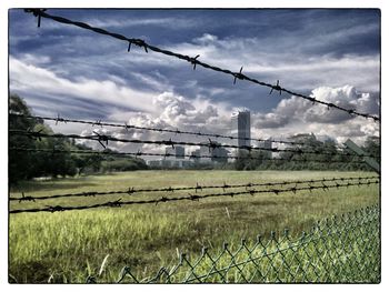 View of field against cloudy sky