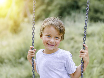 Portrait of smiling boy on swing at playground