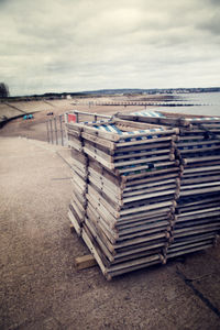 Stack of empty chairs on land against sky