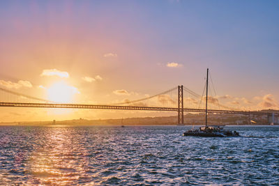 Suspension bridge over river against sky during sunset