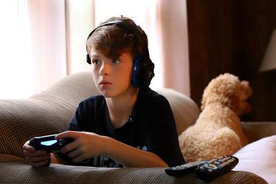 Boy looking away while sitting on sofa at home