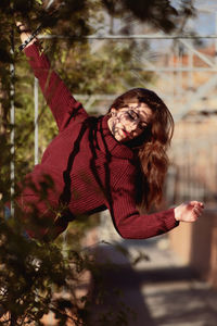 Portrait of young woman standing by tree