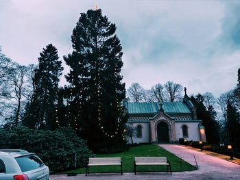 Trees by building against sky