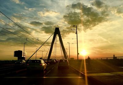 Cars on bridge against sky during sunset