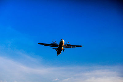 Low angle view of airplane flying against blue sky