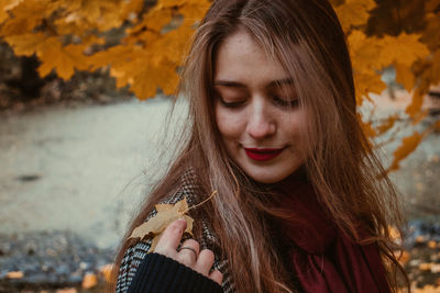 Close-up of woman looking at dry leaf on shoulder