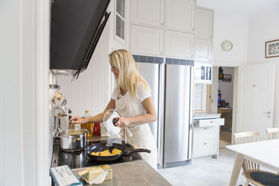 Teenage girl cooking food in kitchen at home