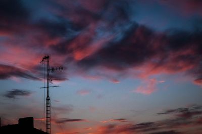 Low angle view of silhouette communications tower against sky during sunset