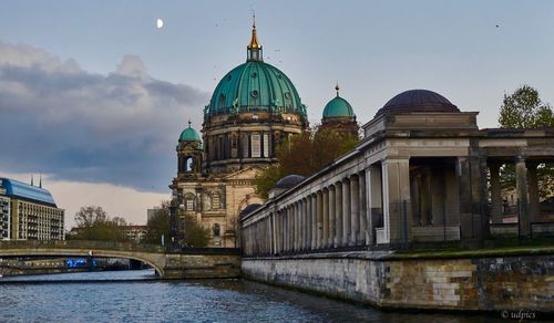 Cathedral by river against sky in city