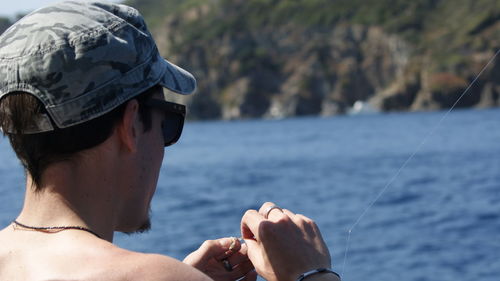 Close-up of shirtless man with sea in background