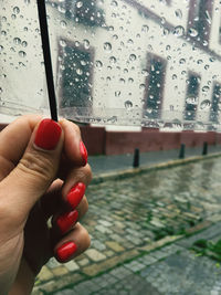 Hand holding wet glass window during rainy season