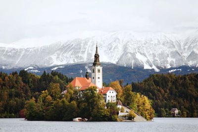 Scenic view of the autumn snow capped mountains against the island at lake bled.
