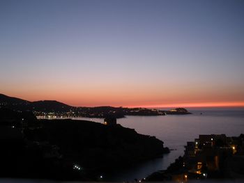 Illuminated houses on mountains overlooking sea at dusk