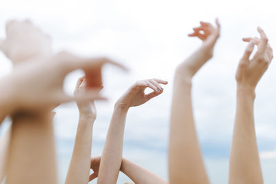 Female friends with raising arms against sky