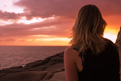 Rear view of woman looking at sea during sunset