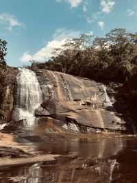 Scenic view of waterfall against sky