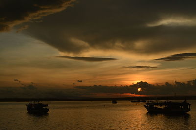 Silhouette boats in sea against sky during sunset