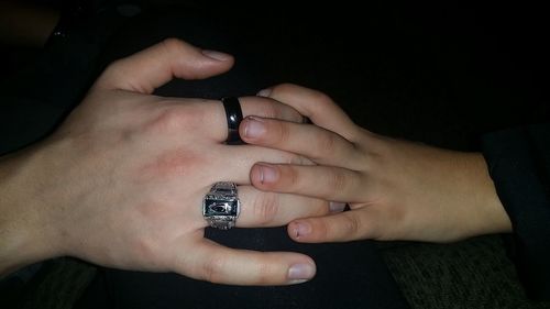 Cropped image of hand holding ring over black background