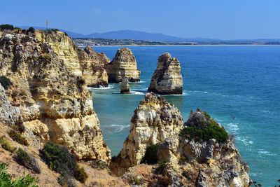 Panoramic view of sea and rocks against blue sky