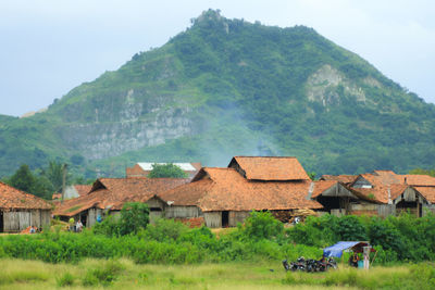 Houses on field by mountain against sky