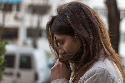 Side view of thoughtful young woman looking down in city