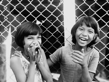 Portrait of smiling girl looking through fence outdoors