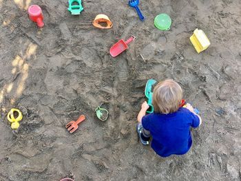 Directly above shot of little boy playing with toys at beach