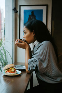 Woman looking away while sitting on table at home