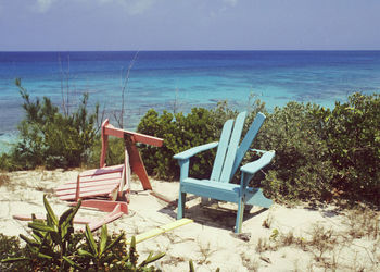 Empty chairs on beach against sky