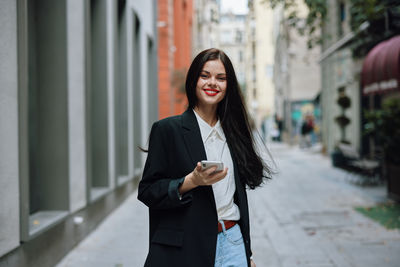 Portrait of young woman standing against building