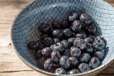 Organic blueberries in a blue and white bowl on the rustic wood background of an old farm table 