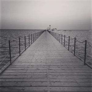 Wooden pier on sea against clear sky