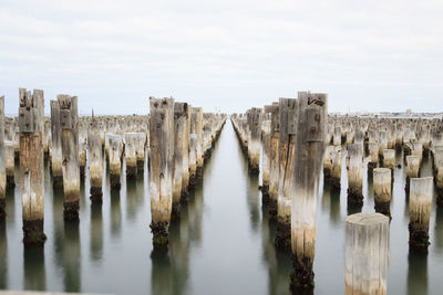 Panoramic view of wooden posts in sea against sky