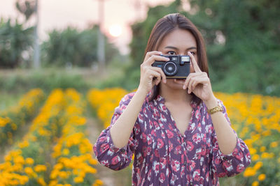 Young woman photographing with camera on field