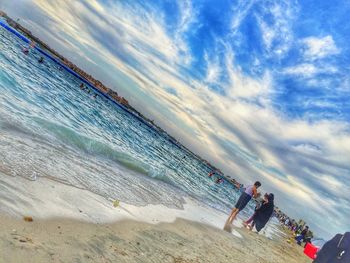 Panoramic view of people on beach against sky