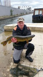 Man holding catch of fish at pier