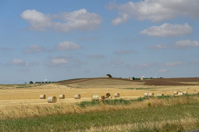 Hay bales on field against sky