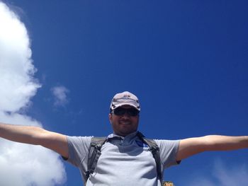 Low angle portrait of man standing against blue sky