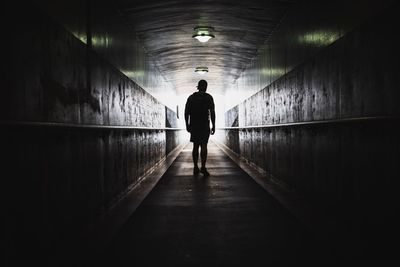 Rear view of silhouette man standing in tunnel