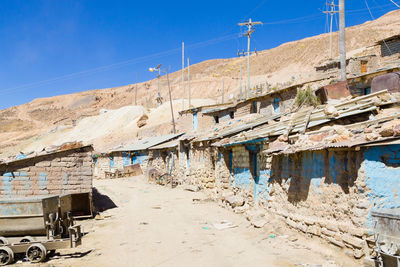 Low angle view of abandoned buildings against clear blue sky