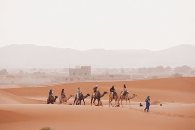 People riding horse on desert against sky