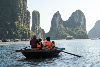 Rear view of people on rock in sea