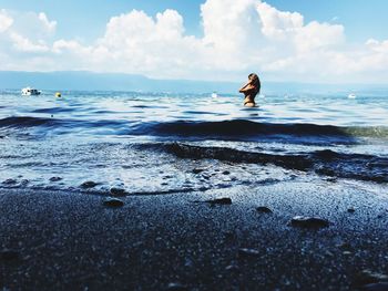 Man on rock in sea against sky