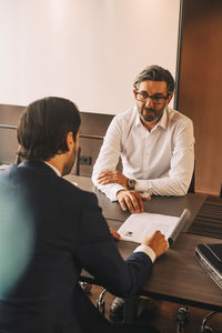 High angle view of advisor explaining document to businessman in meeting at law office